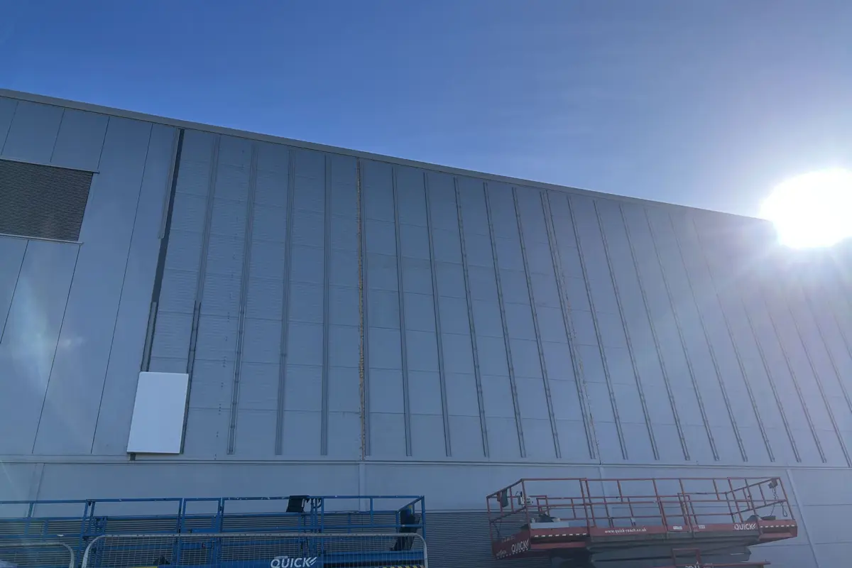 A silver-grey composite panel elevation with scissor lifts at its base