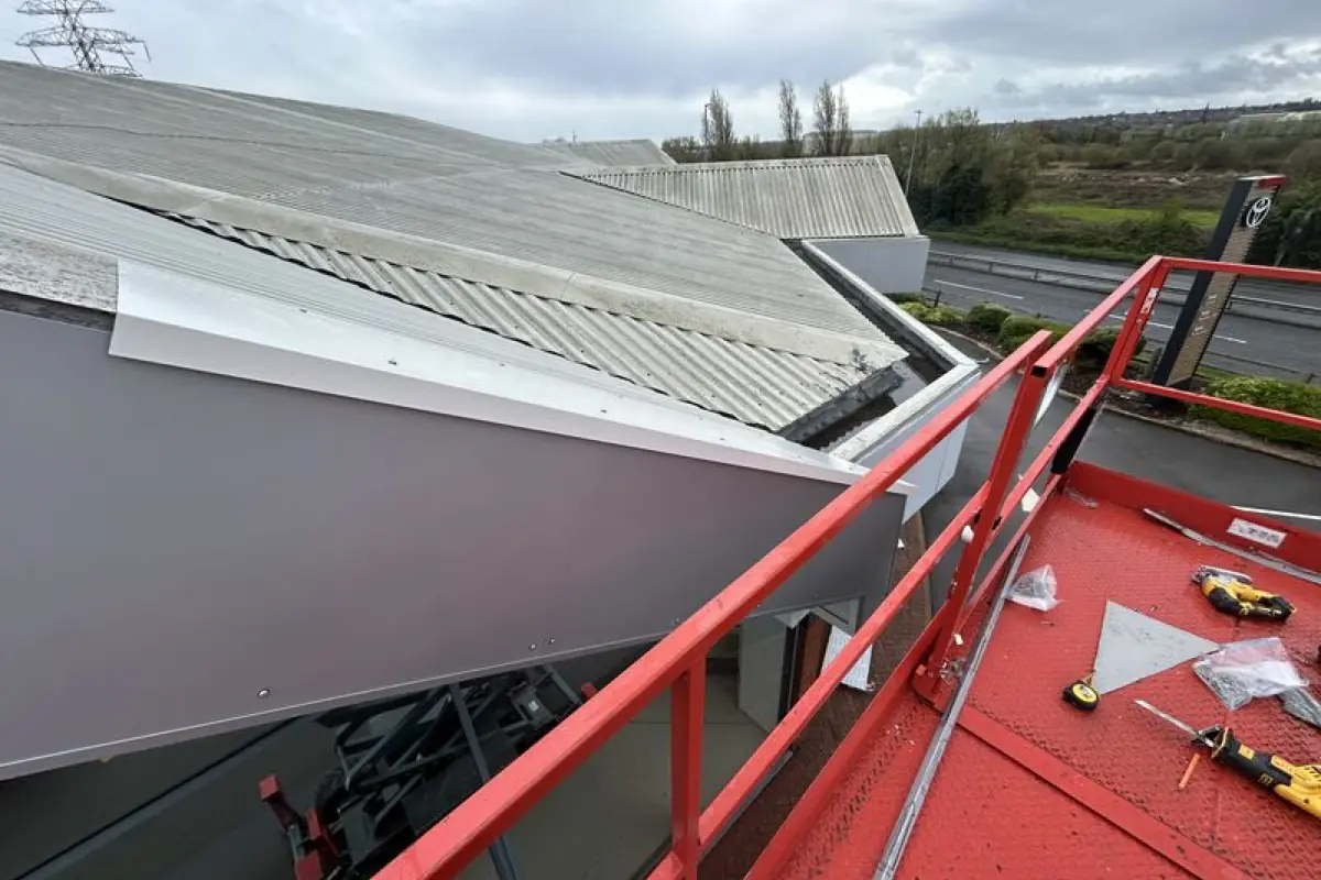 An old cement sheet dealership roof beside newly installed fascia and canopy metalwork