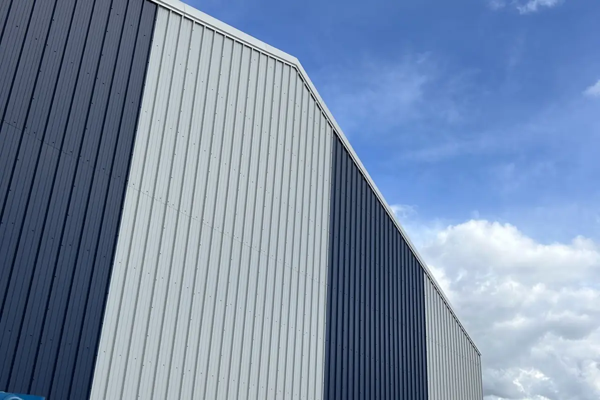 A tall warehouse elevation in navy and silver profiled wall cladding against a blue sky